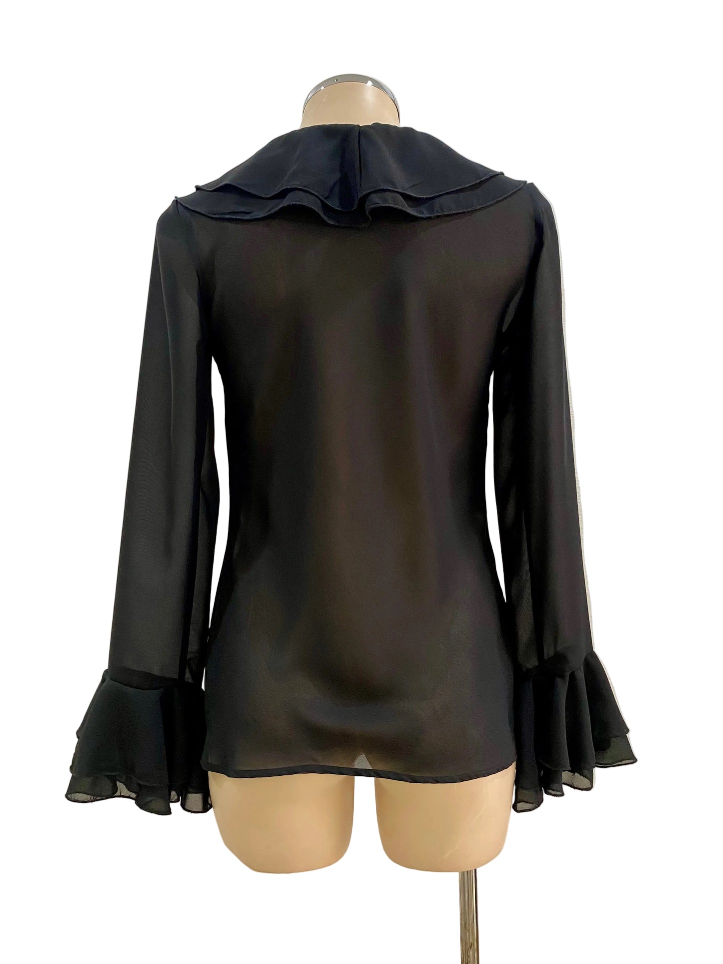 Black blouse with ruffled collar and cuffs on a mannequin against a white wall.