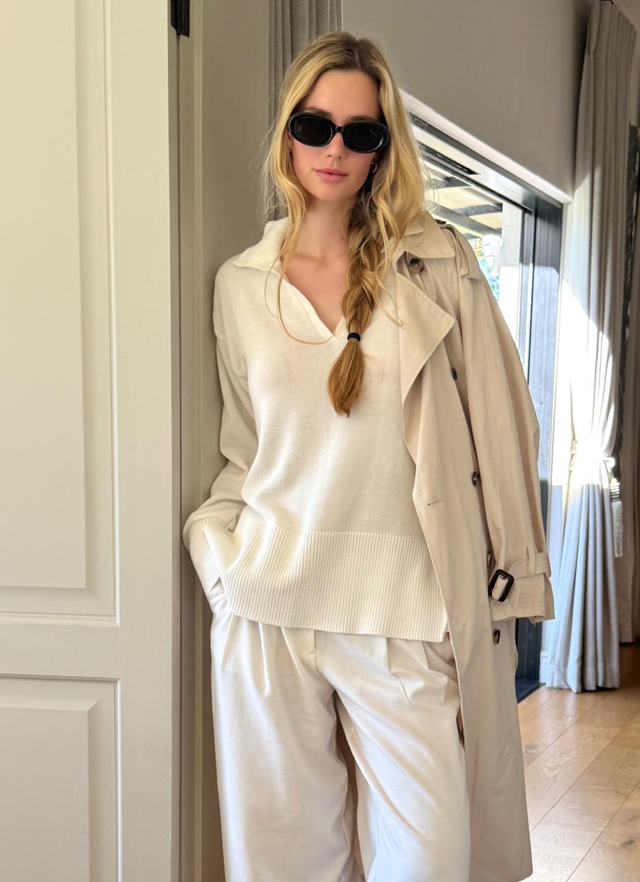 Woman in a Ivory outfit with beige trench coat and standing indoors.