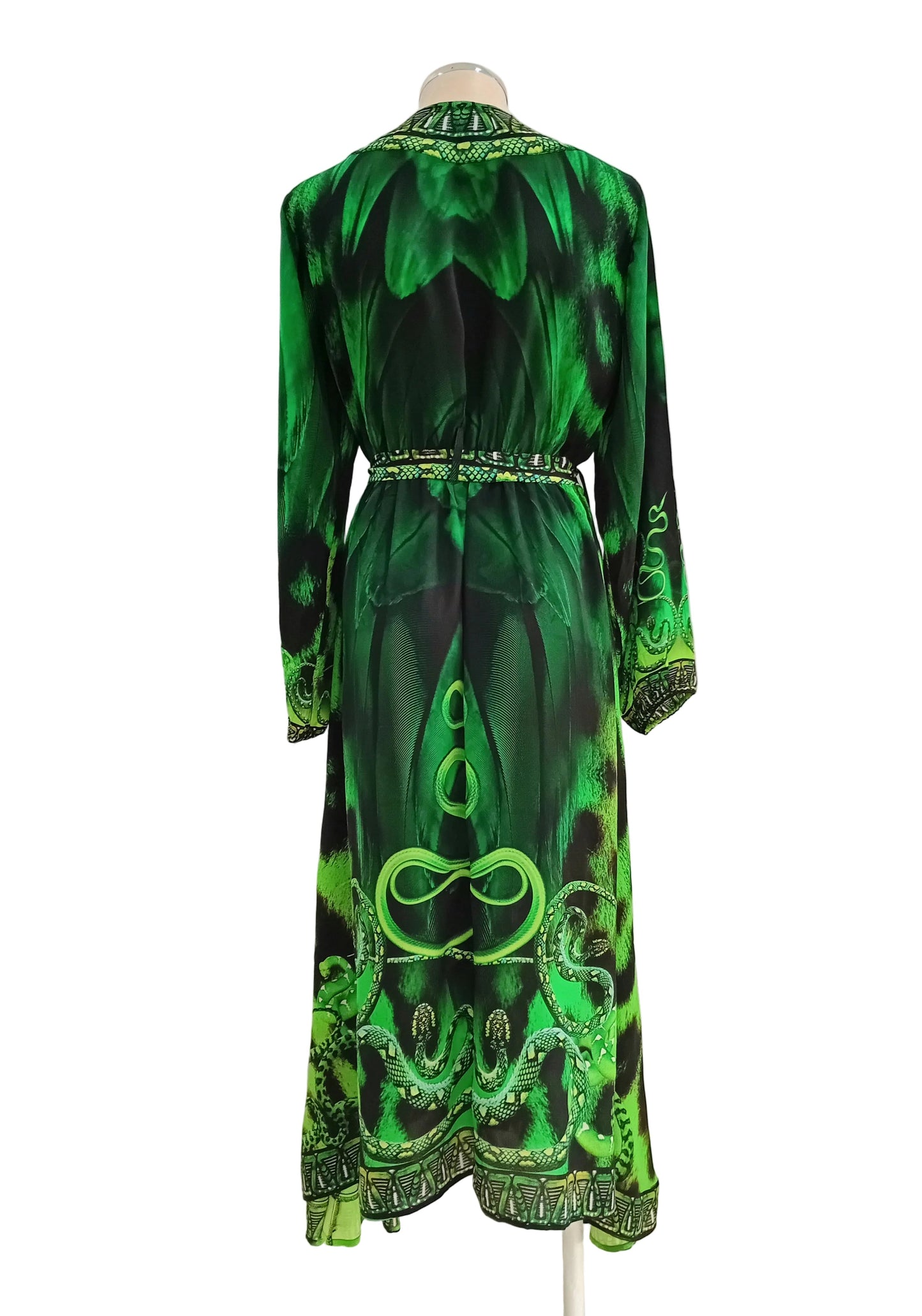 Madusa Green and black patterned wrap dress against a white wall.