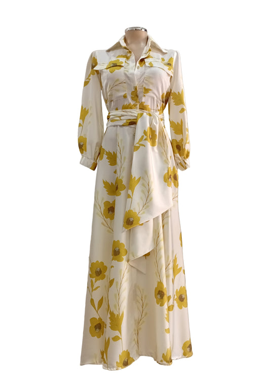White dress with yellow floral pattern on a mannequin against a white wall.