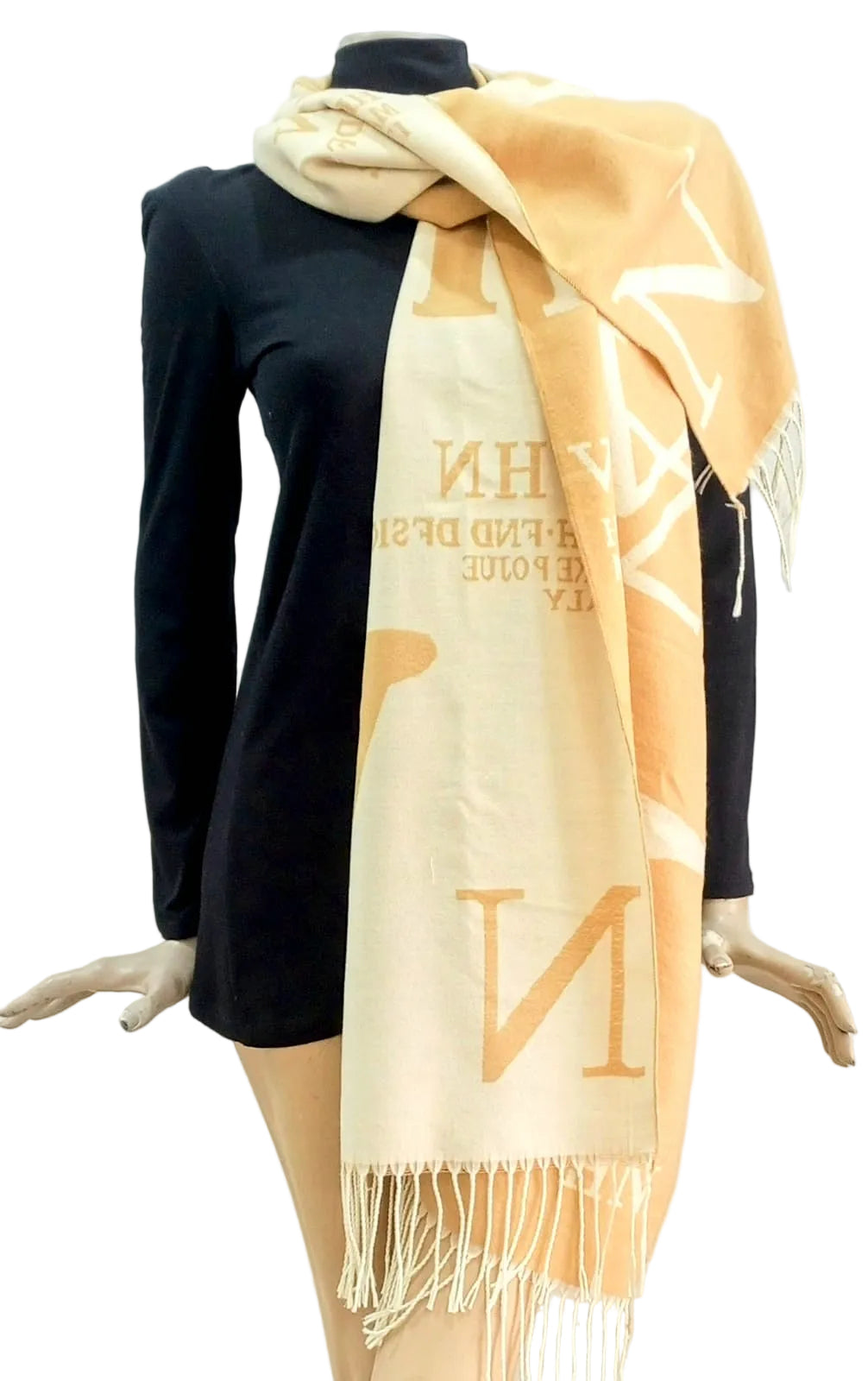 Mannequin wearing a black dress with a beige scarf featuring white text and fringes.