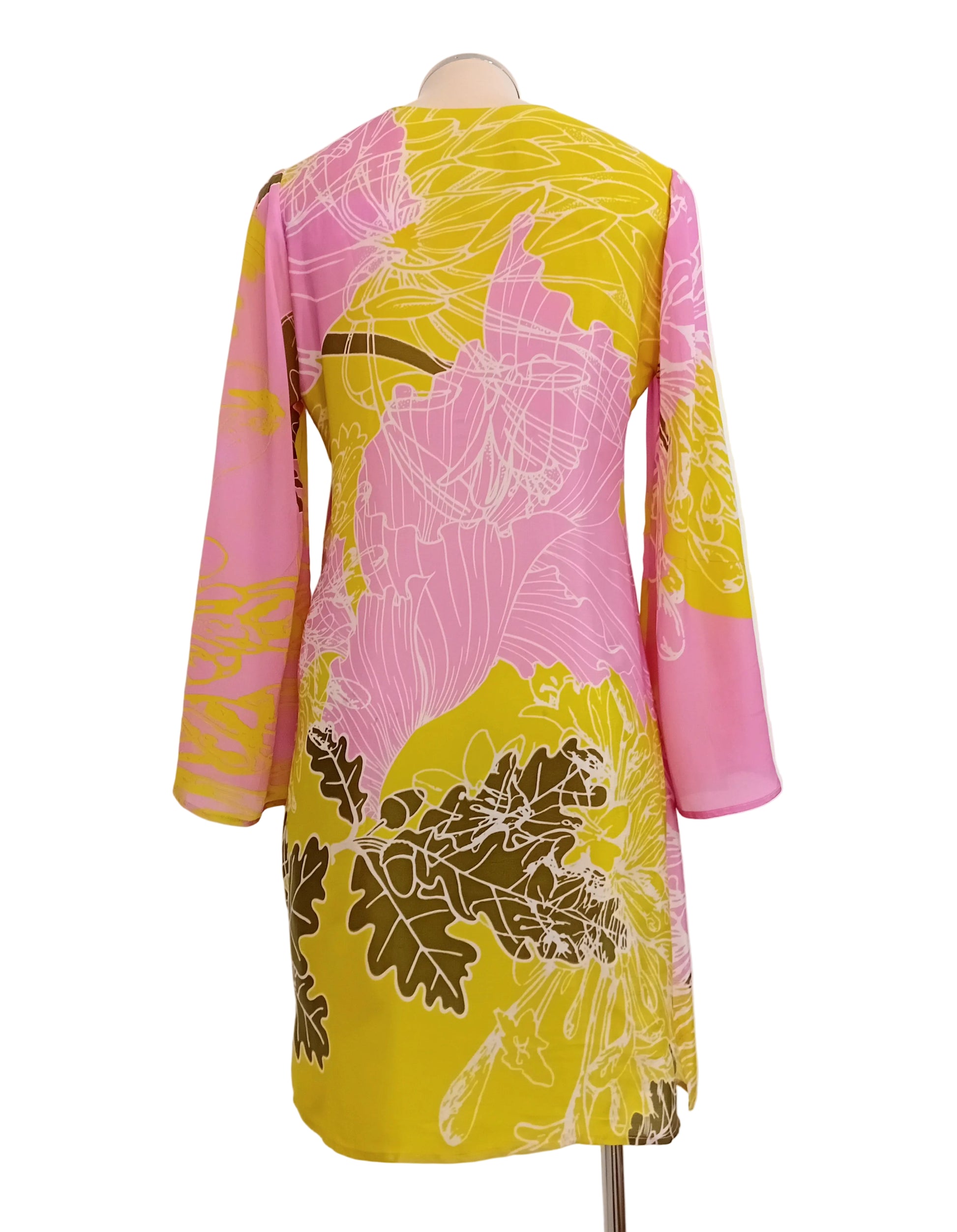 Colourful tunic dress with pink and yellow lime floral pattern against a white wall.