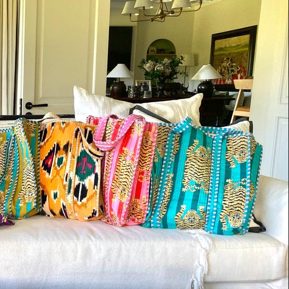 Colorful patterned tote bags on a white sofa in a living room setting.