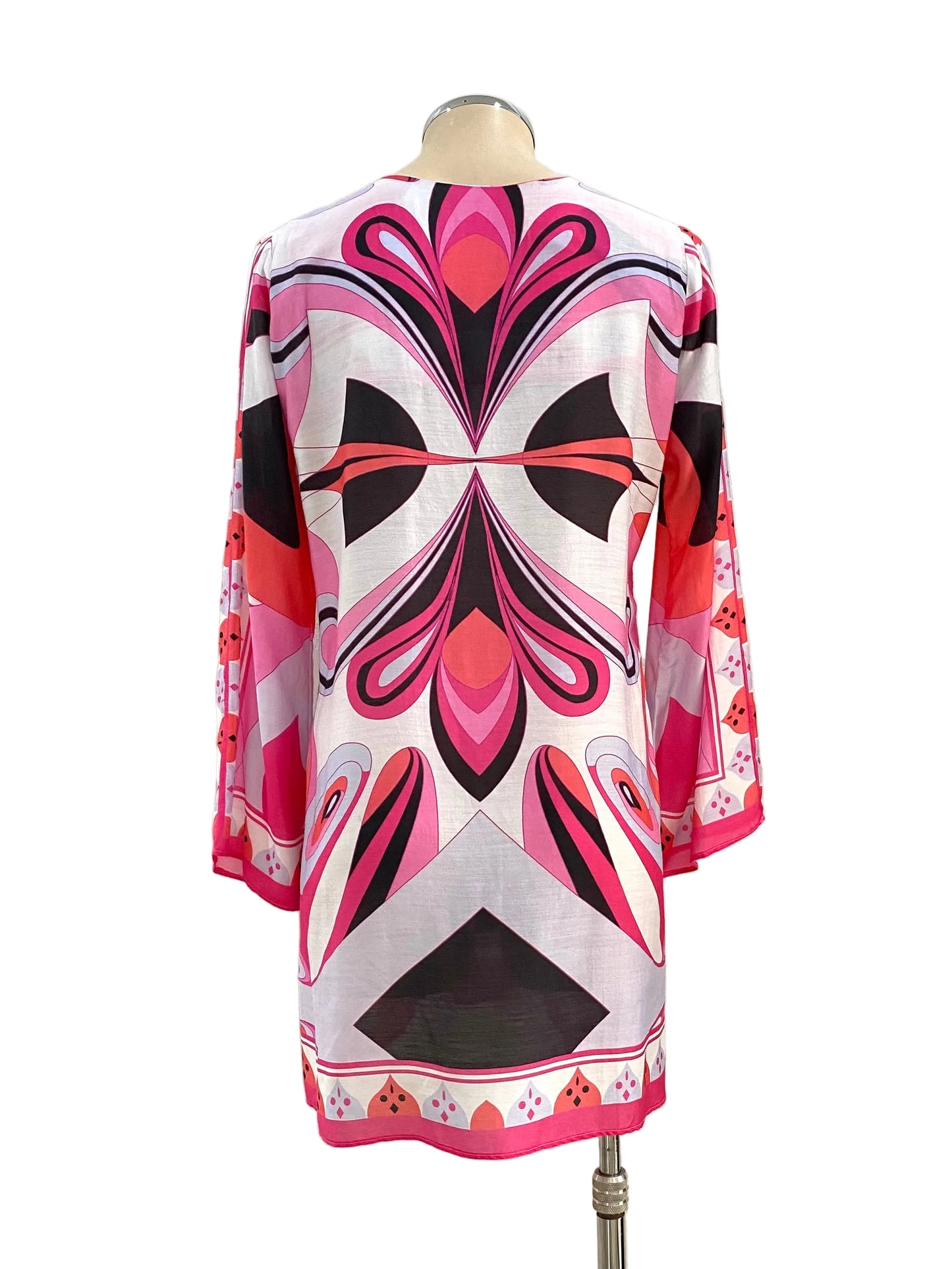 Mannequin wearing a colorful dress with geometric pattern against a white wall.