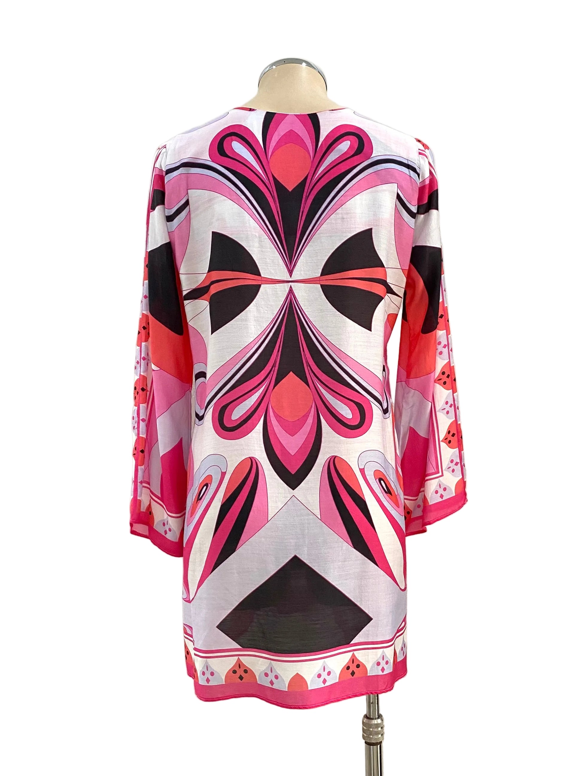 Mannequin wearing a colorful dress with geometric pattern against a white wall.