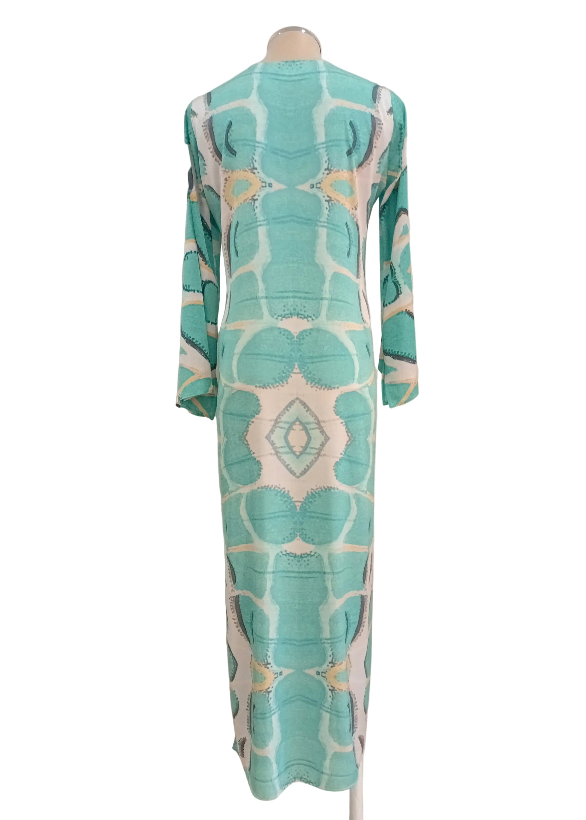Teal and white patterned tunic dress against a neutral wall.