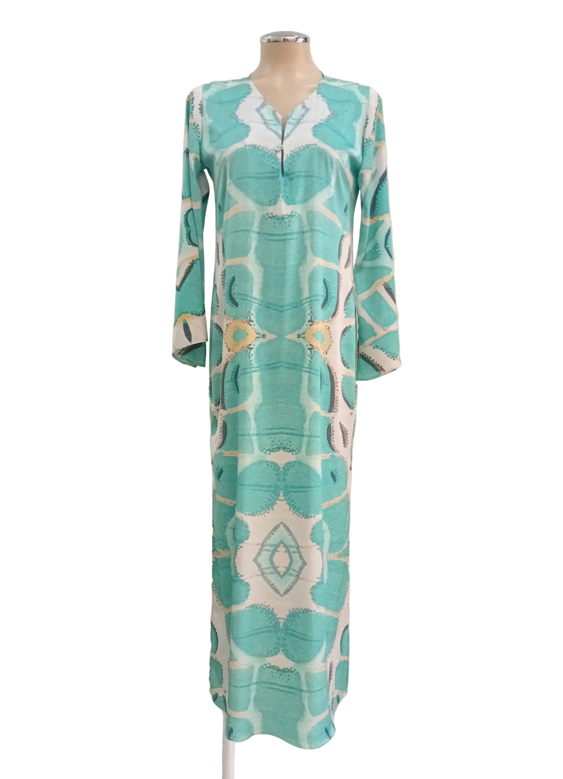 Turquoise patterned dress against a white wall.