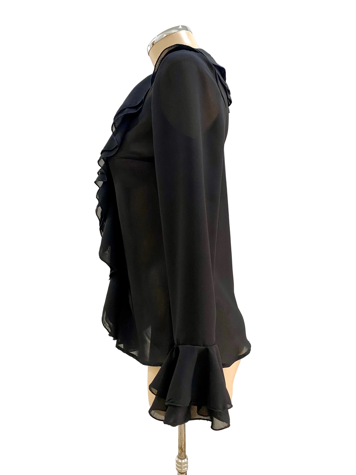 Black ruffled blouse on a mannequin against a white wall.
