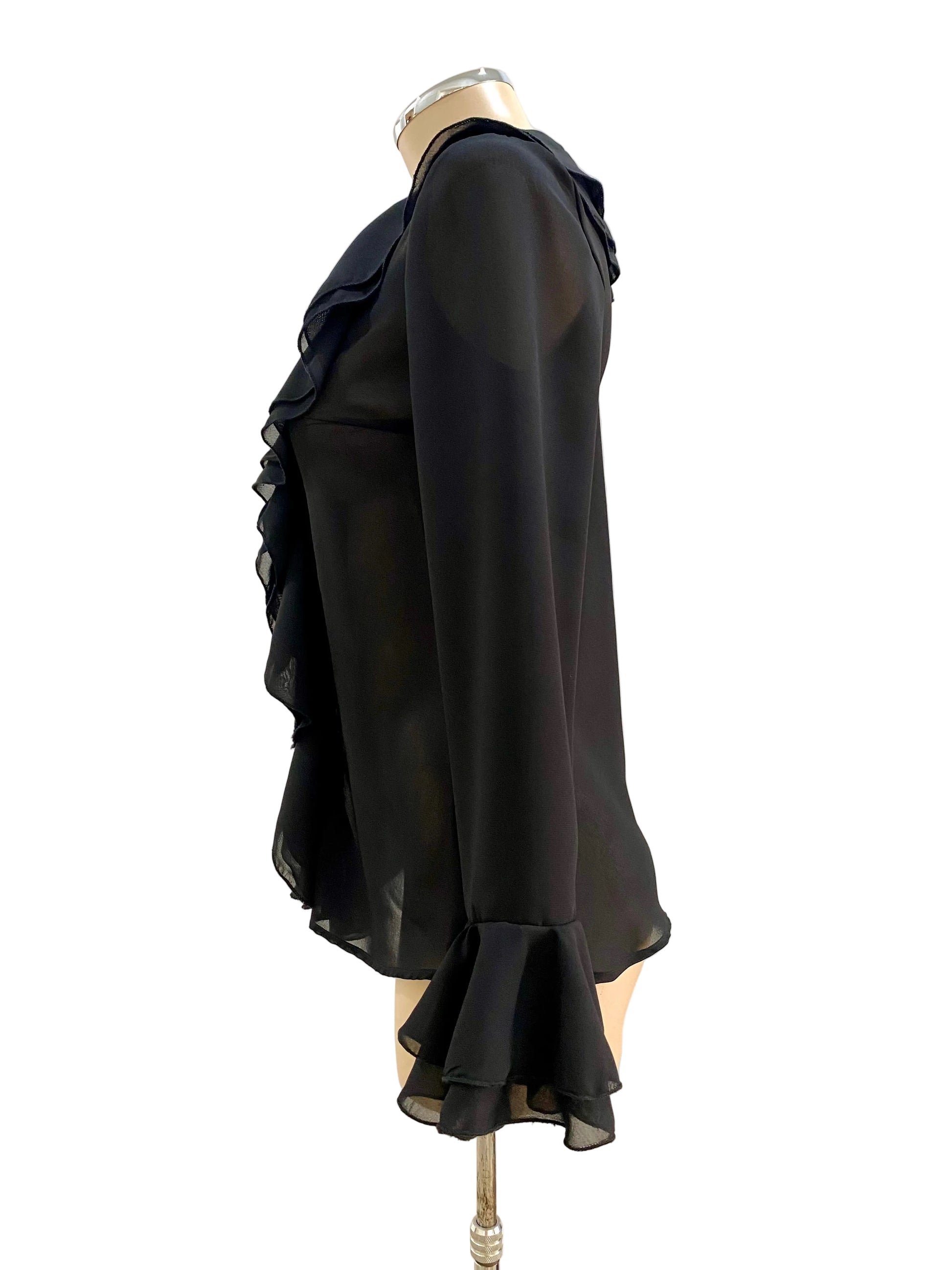 Black ruffled blouse on a mannequin against a white wall.
