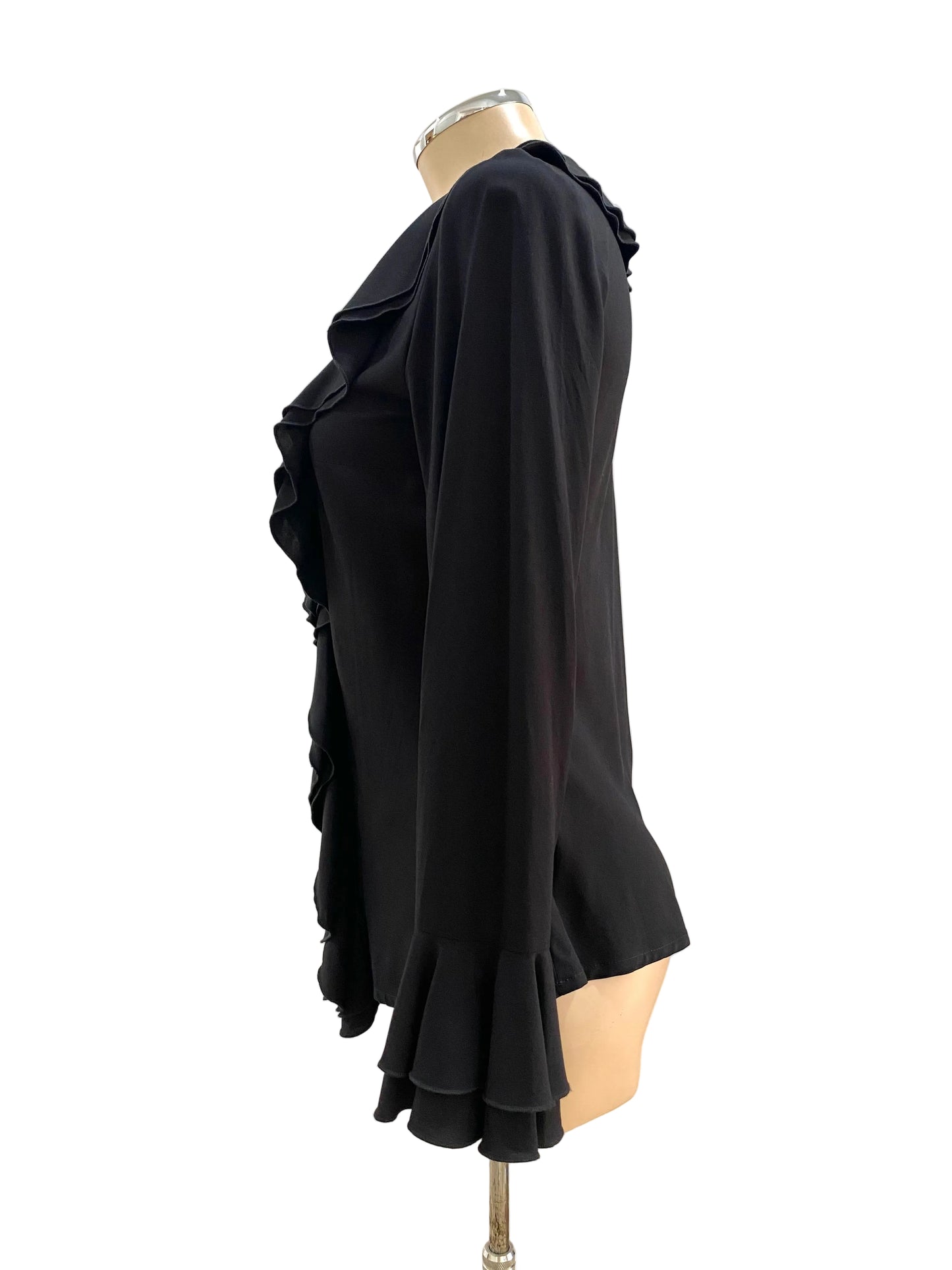 Black ruffled blouse on a mannequin against a white wall.