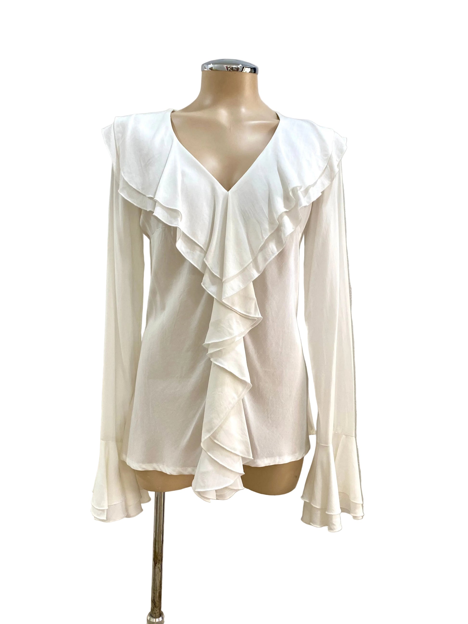 White ruffled blouse on a mannequin against a white wall.