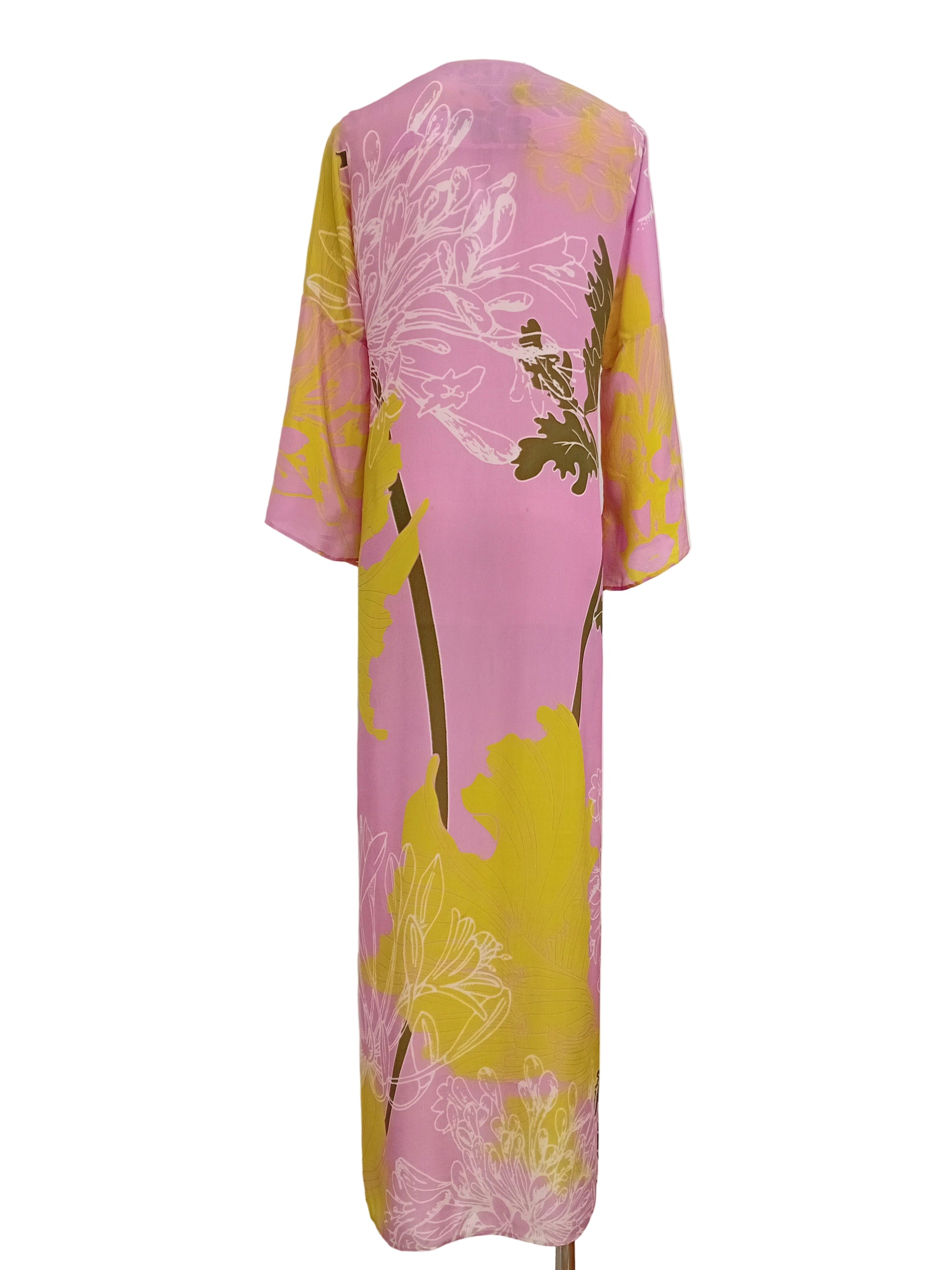 Tunic dress with pink and yellow lime floral pattern against a white wall.