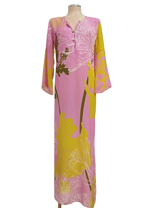 Tunic dress in a pink and lime yellow floral dress against a white wall.