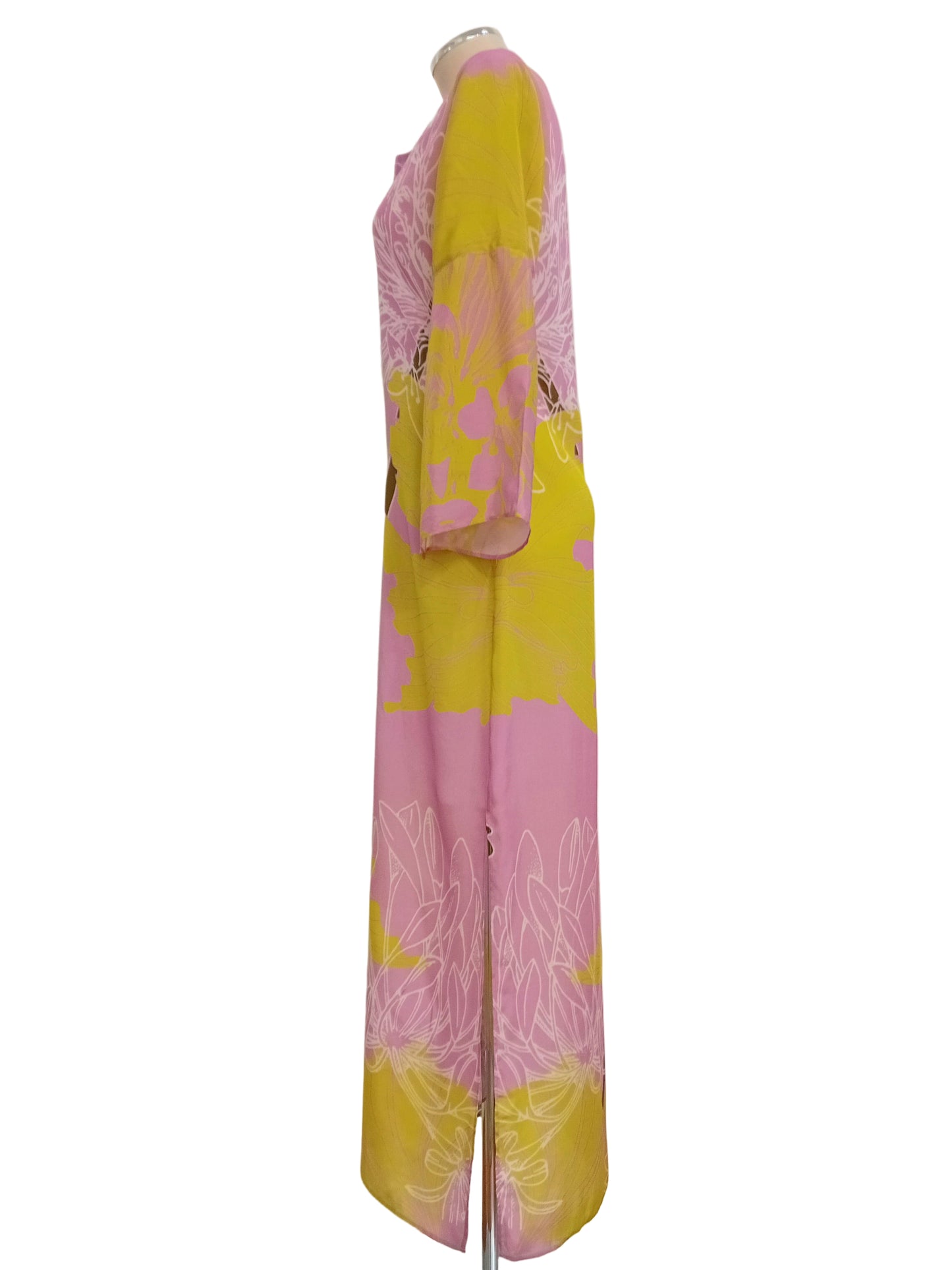 Tunic dress in a floral pink and lime yellow pattern against a white wall.