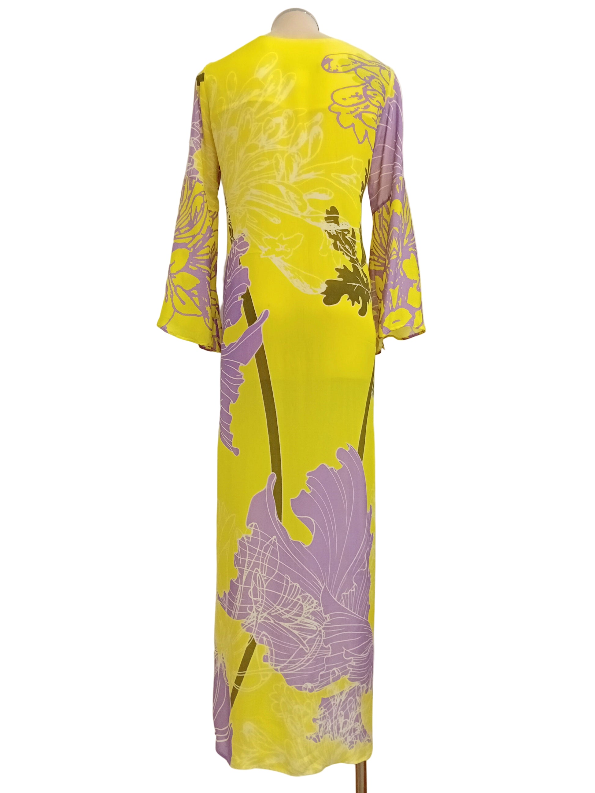 Tunic dress with yellow and purple floral pattern against a white wall.